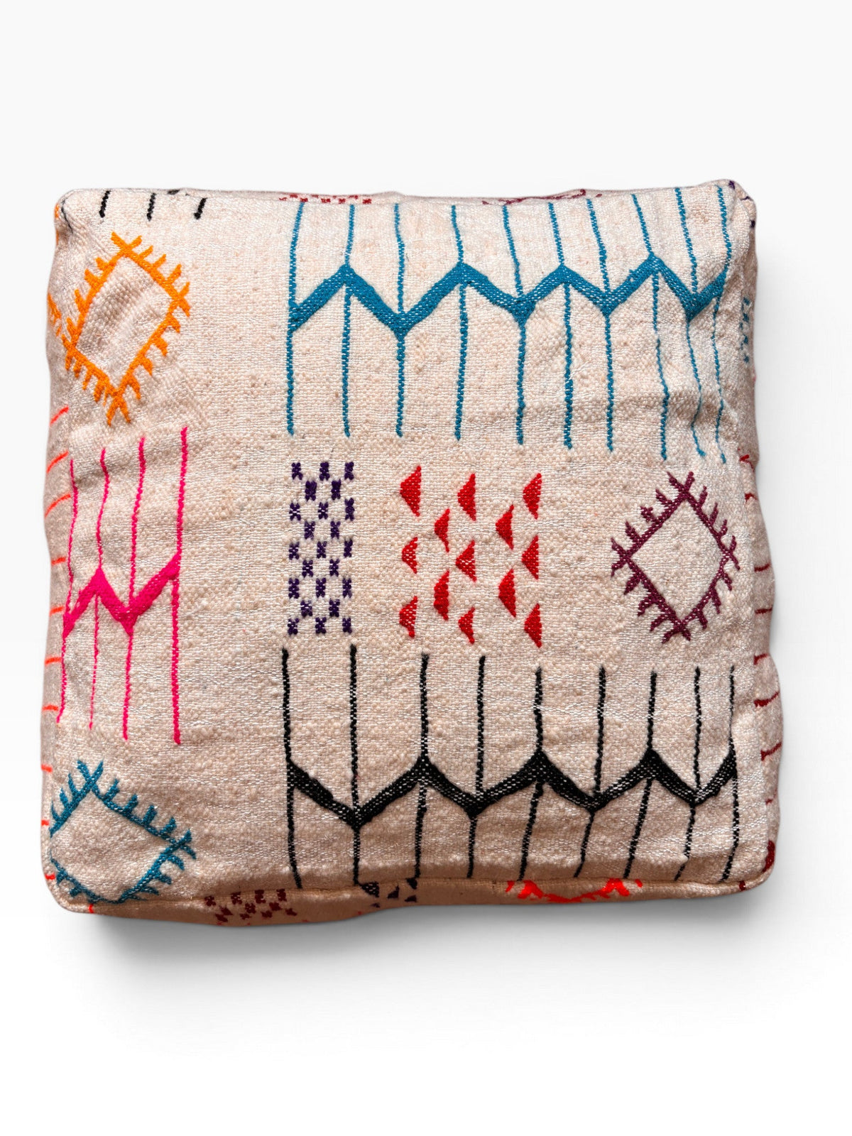 Ein gefaltetes LEY! Bodenkissen - Colorful Line - Lana in Beige mit lebendiger geometrischer Stickerei in Blau, Pink, Orange und Rot.