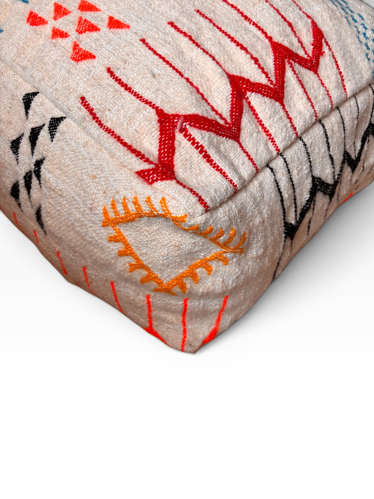 Nahaufnahme des LEY! Bodenkissen - Colorful Line - Laura mit geometrischer Stickerei in Rot, Schwarz und Orange.