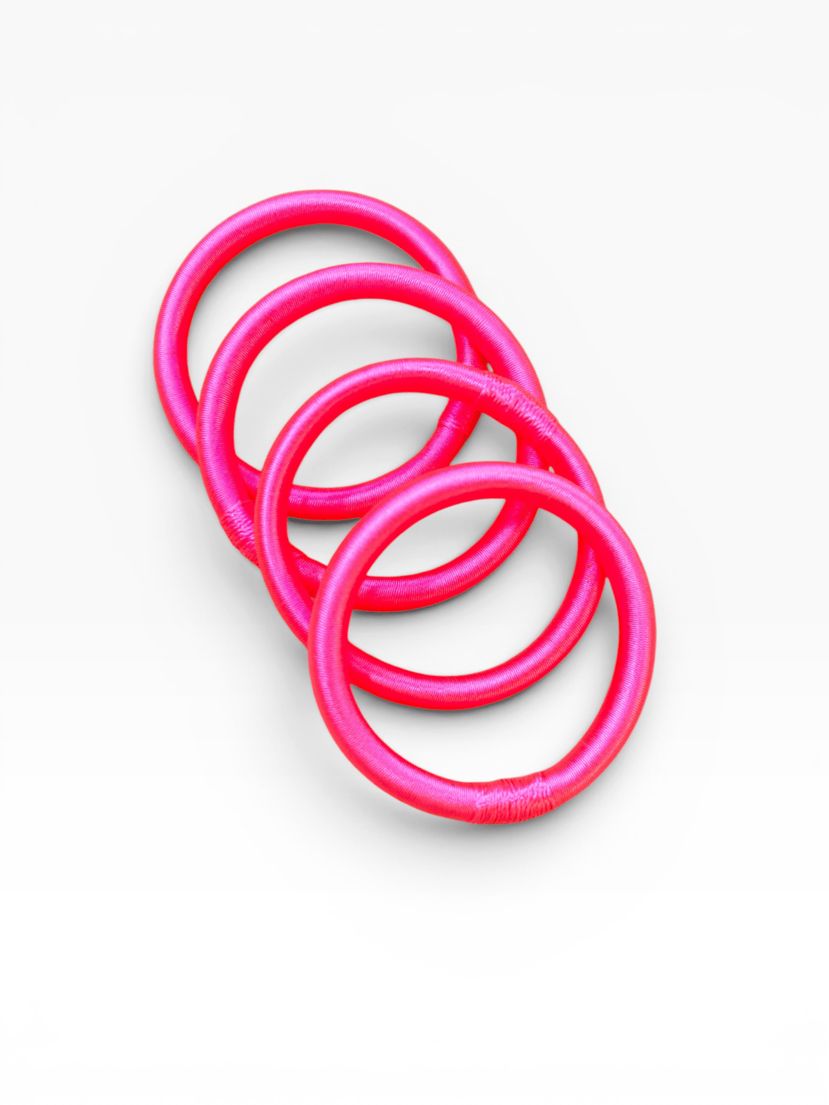 LEY! Armreif „Minama“ in Neonrosa, marokkanisch inspiriert, diagonal auf weißem Hintergrund angeordnet.