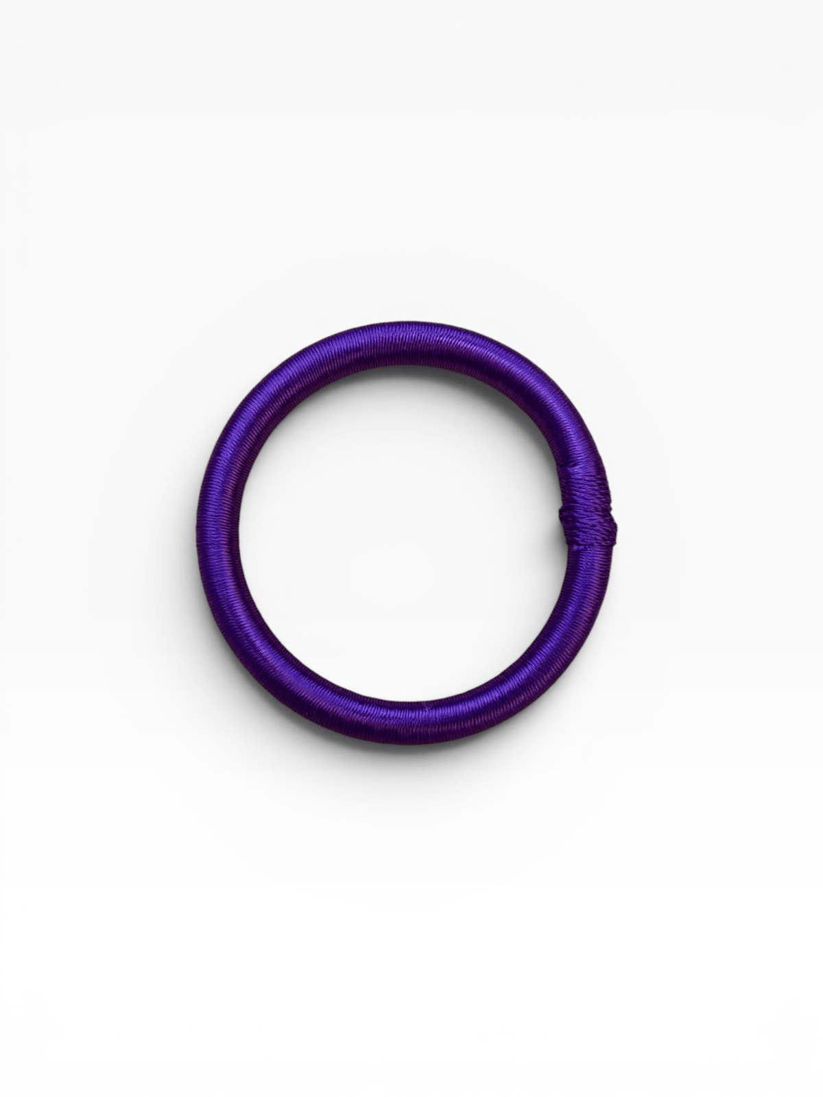 Ein violetter LEY! Armreif – Minama – in Lila liegt flach auf einem weißen Hintergrund und erinnert an ein Haargummi.