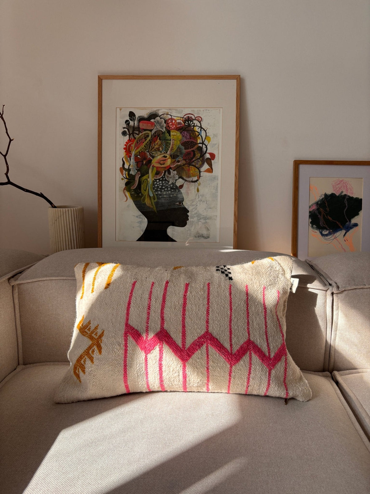 Ein beiges Sofa mit einem LEY!-Kissen – „Colorful Line“; an der Wand dahinter ist ein abstraktes Kunstwerk gerahmt und ausgestellt.