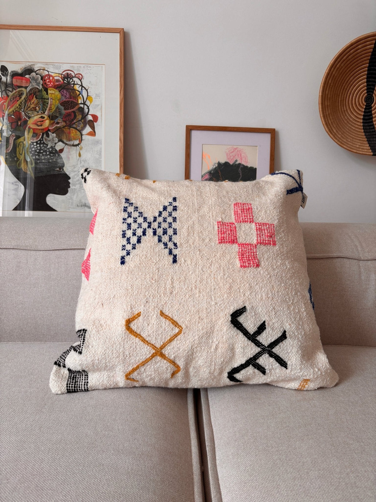 LEY! Kissen – „Colorful Line“, 60 x 60 cm von LEY! mit geometrischen Mustern auf dem Sofa, einem gerahmten Bild und einem Korb im Hintergrund.