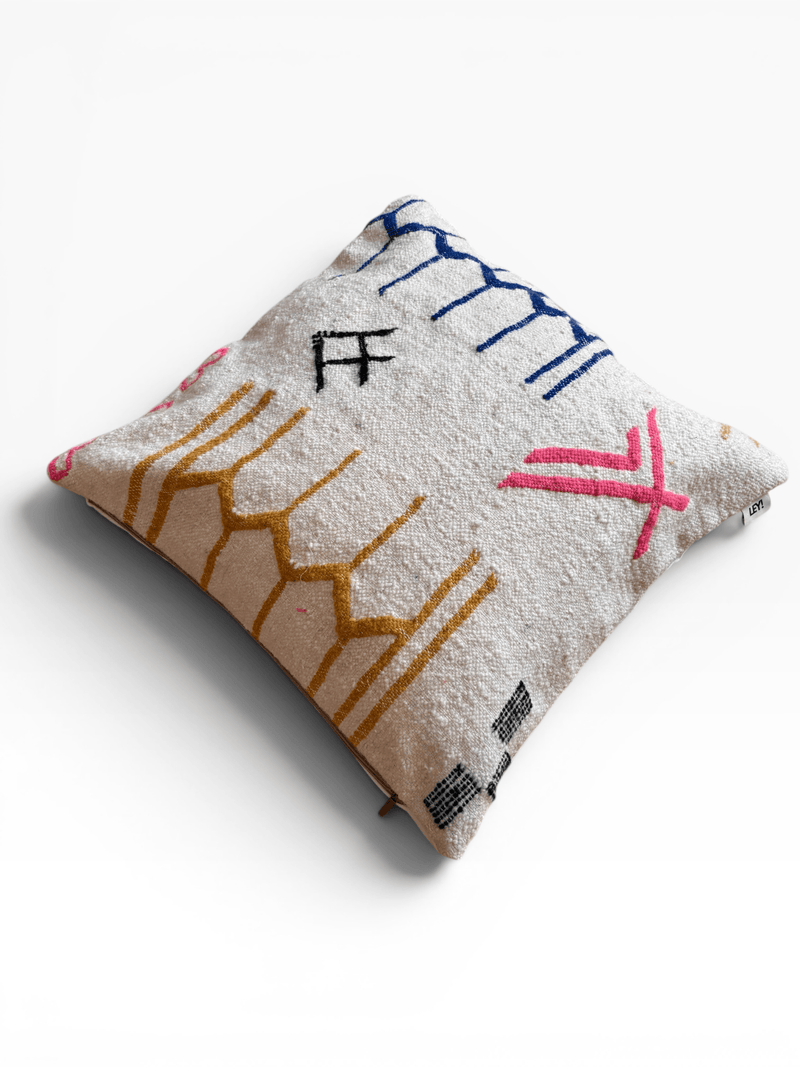 LEY! Kissen – Colorful Line (60 x 60): Ein LEY!-Kissen mit abstrakten gelben, blauen, rosa und schwarzen Linien auf strukturiertem Stoff.