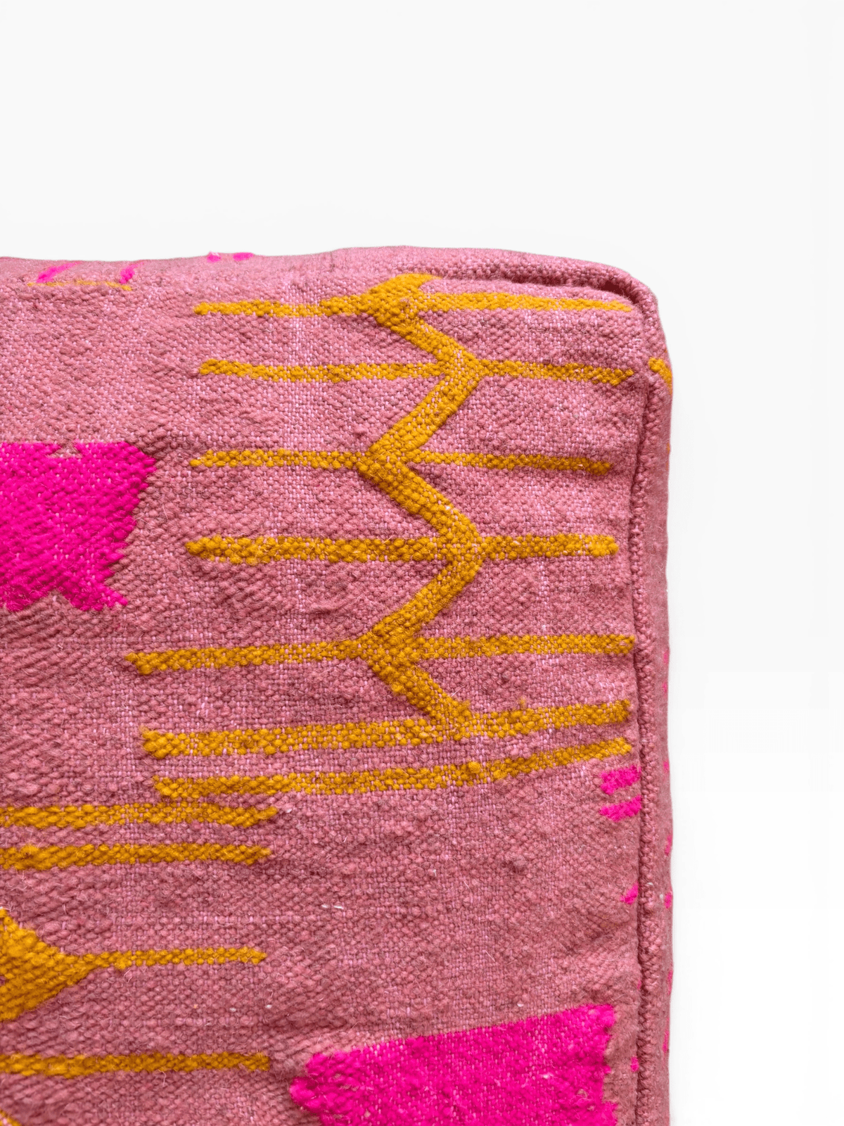 Nahaufnahme von LEY! Bodenkissen – Colorful Line Terra III in Terrakotta mit gelbem Zickzackmuster und leuchtend pinken Akzenten.