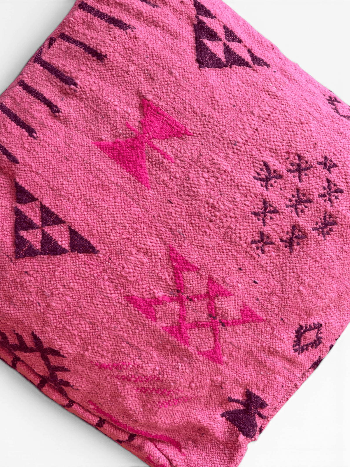 LEY! Bodenkissen – Colorful Line – Pink Edition: rosa Bodenkissen aus Wolle mit violetten geometrischen Dreiecken auf weißem Hintergrund.