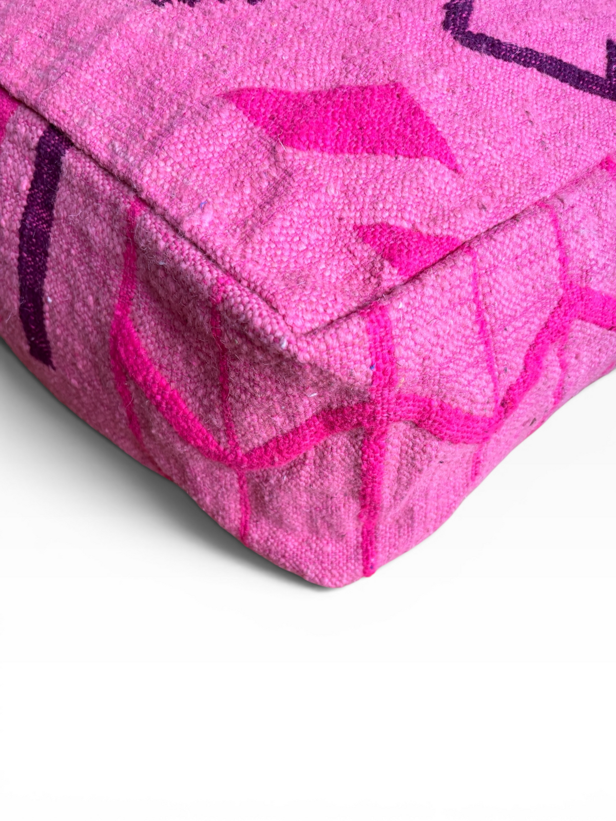 Eine Nahaufnahme des LEY! Bodenkissens – Colorful Line – Pink Edition mit violetten Mustern auf strukturierter Schurwolle.