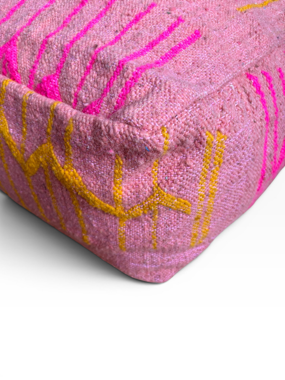 Nahaufnahme des „Bodenkissen“ von LEY! – „Colorful Line Terra IX“, mit neonpink-gelber Stickerei auf terrakottafarbener gewebter Wolle.