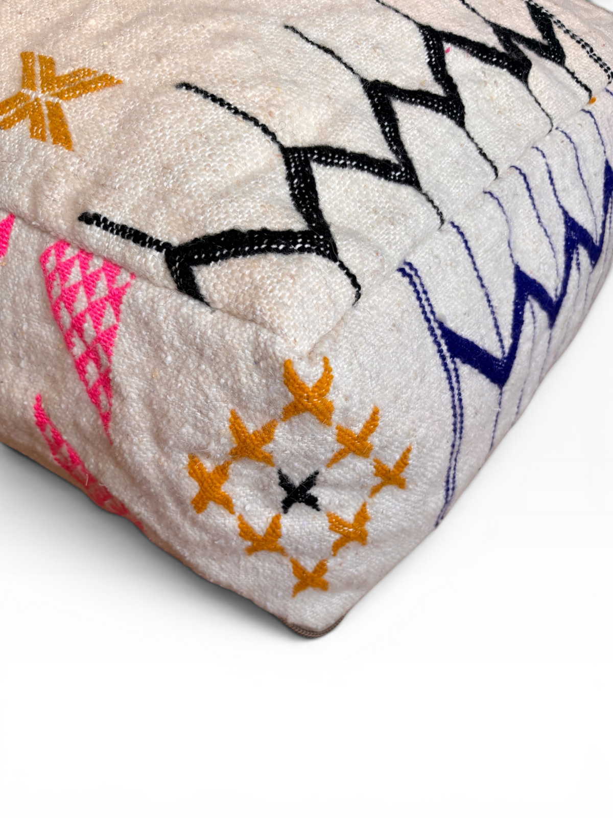 Ein weißes LEY! Bodenkissen – Colorful Line – Lavina mit schwarzen, gelben, rosa und blauen geometrischen Stickereien.