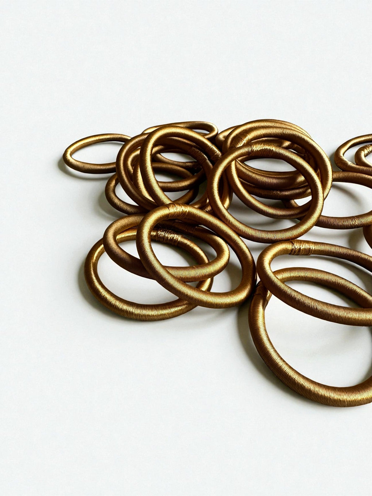 Ein Stapel LEY! Armreifen – Minama – in Goldgelb, jeder mit einem einzigartigen, marokkanisch inspirierten Design.