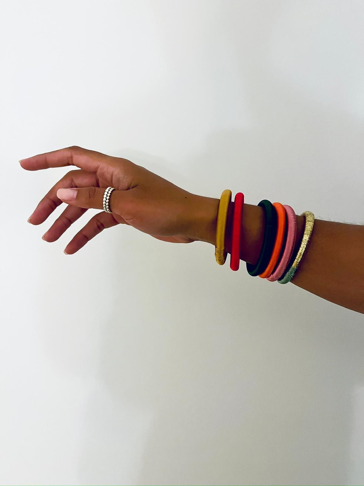 Eine Hand trägt Ringe und den LEY! Armreif – Minama – in der Farbe „Mint“ vor einem schlichten weißen Hintergrund.