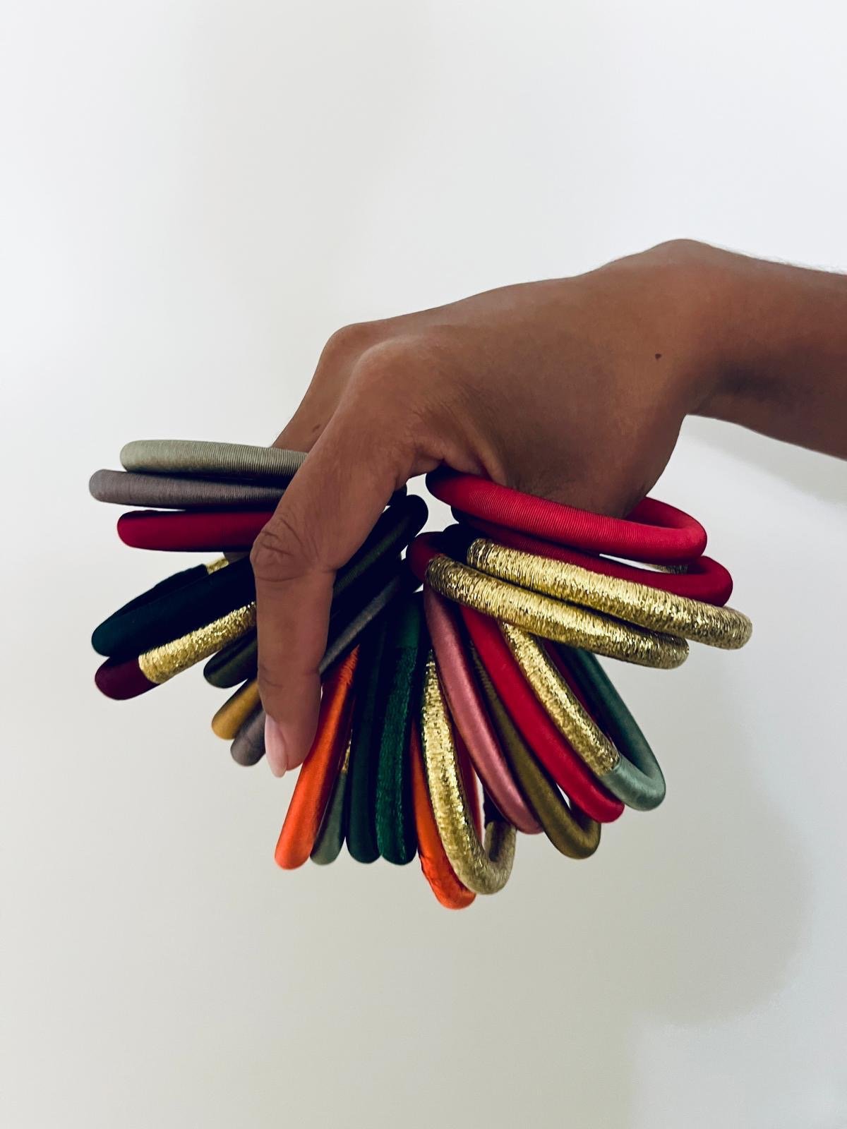 Eine Hand hält den LEY! Armreif – Minama – mint, dessen Farben an marokkanischen Schmuck auf weißem Hintergrund erinnern.