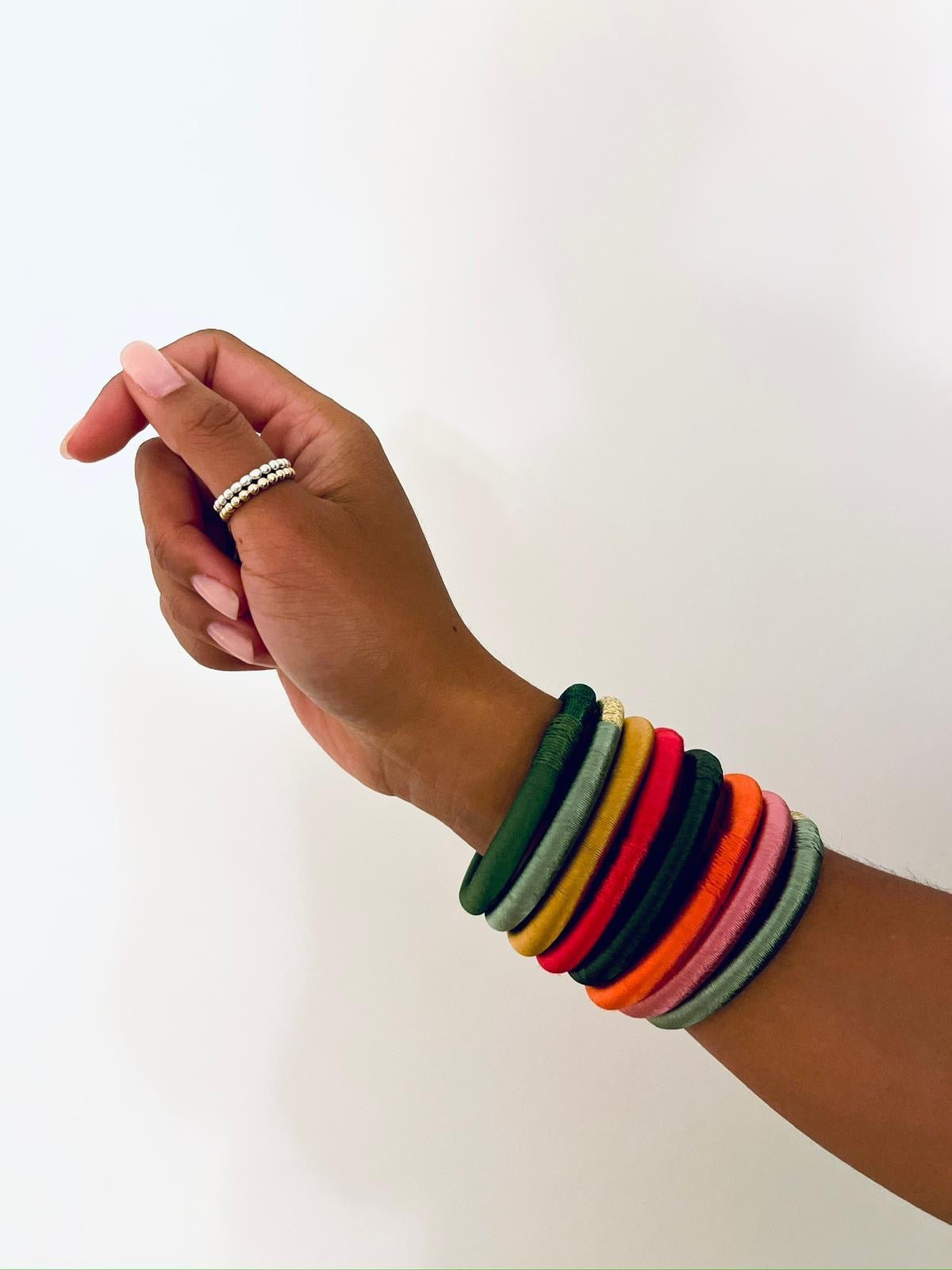 Eine Hand mit einem Perlenring und dem Armreif „LEY!“ von Minama in der Farbe „Mint“ ragt vor einem weißen Hintergrund hervor und erinnert an marokkanischen Stil.