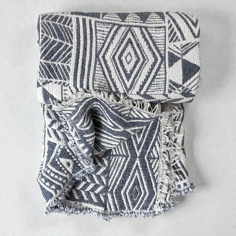 Die CALMA Musselin Decke von LEY! in Grau-Weiß (1,50 x 2,40 m) zeichnet sich durch ein gewebtes Design mit luftiger Struktur und Fransen aus - perfekt, um Ihrem Raum einen gemütlichen Boho-Design-Stil zu verleihen.